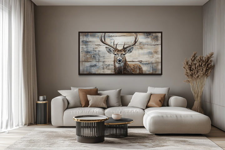 Rustic deer painting on wood canvas wall art hanging above a modern sofa in a cabin-style room.