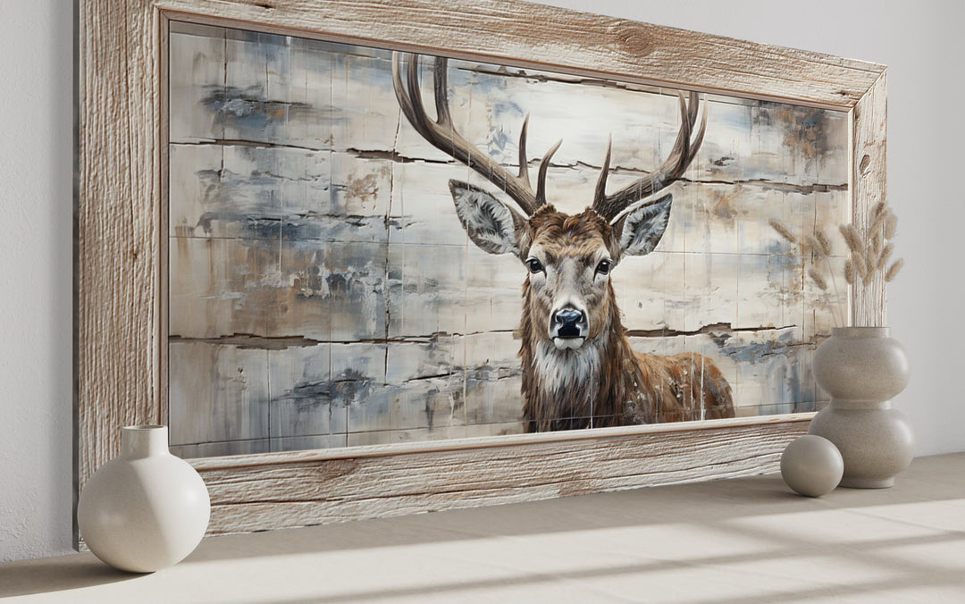 Rustic deer painting on wood-textured canvas in a wooden frame, styled with neutral vases.