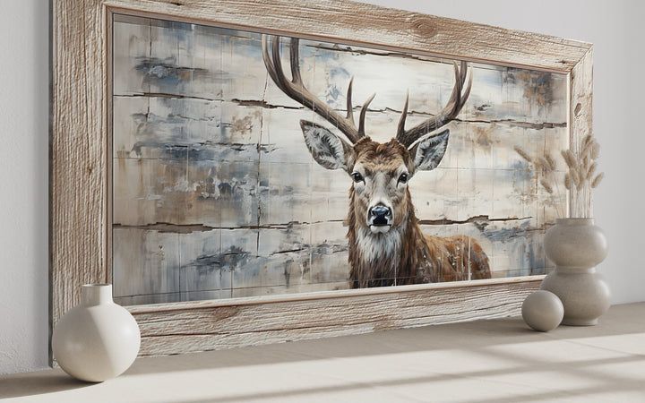 Rustic deer painting on wood-textured canvas in a wooden frame, styled with neutral vases.
