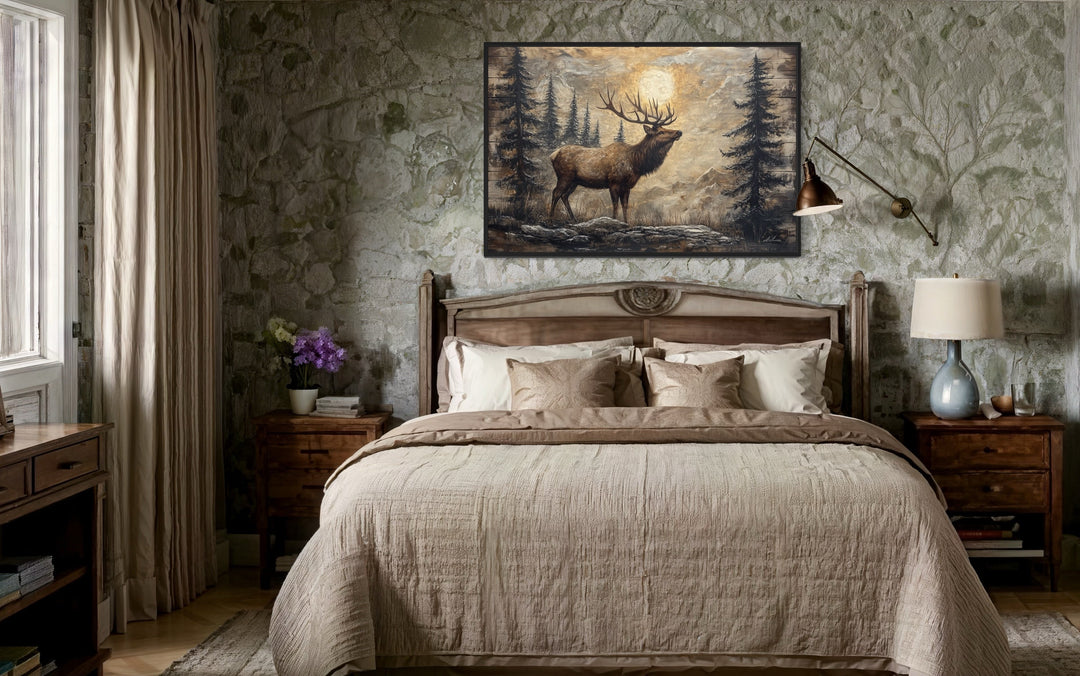 Rustic elk in winter forest painted on wood framed canvas wall art above a bed in a cabin bedroom.
