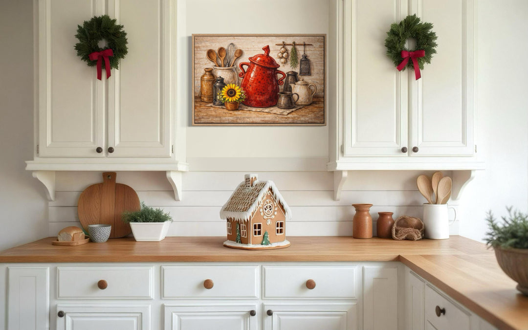 Rustic farmhouse kitchen wall art featuring a red ceramic pot and utensils on a wooden surface.
