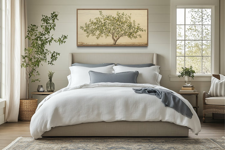 Rustic farmhouse apple tree canvas wall art in a wooden frame hanging above a cozy bed.