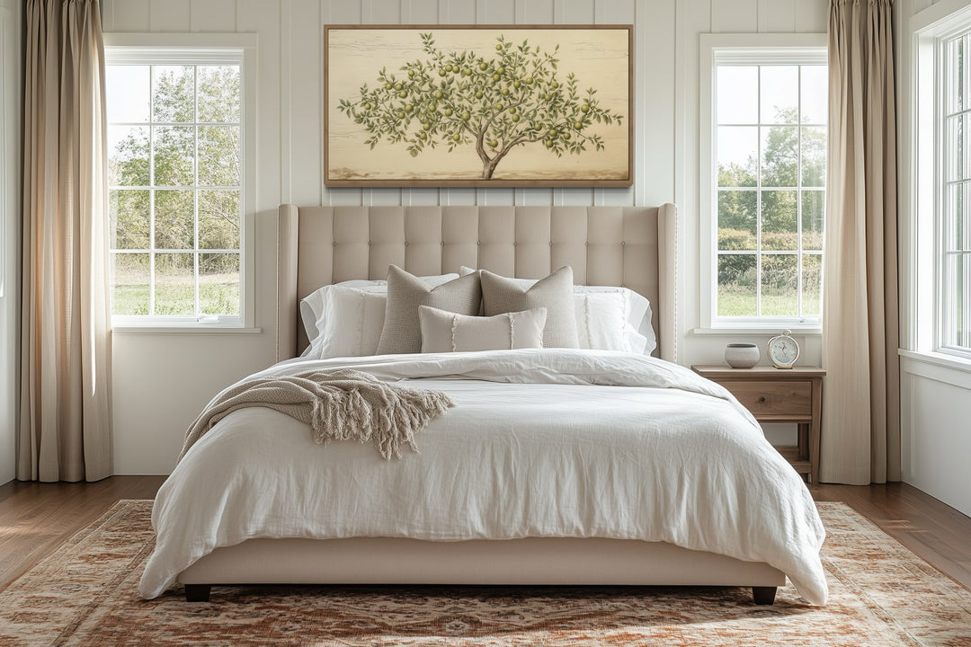 Rustic farmhouse apple tree canvas wall art in a wooden frame above a beige upholstered bed.