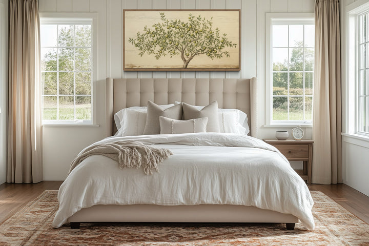 Rustic farmhouse apple tree canvas wall art in a wooden frame above a beige upholstered bed.