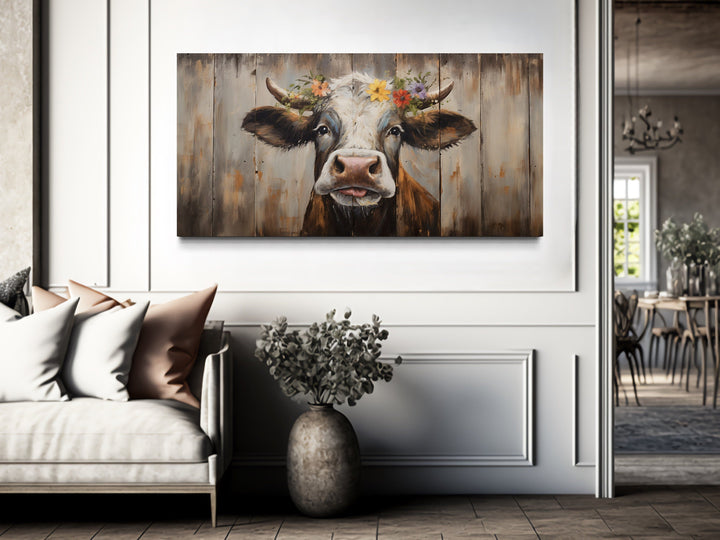 Rustic farmhouse wall art featuring a curious cow painting with a floral crown on wood-look canvas.