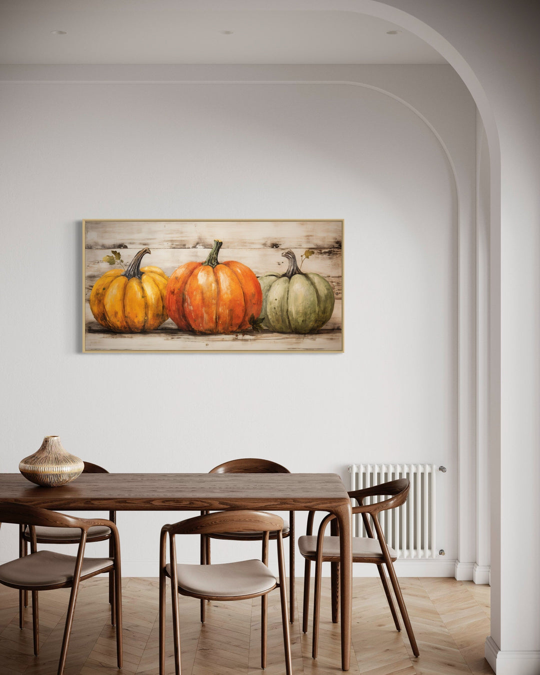 Rustic farmhouse wall art featuring three pumpkins on a wood-style background in a dining room.