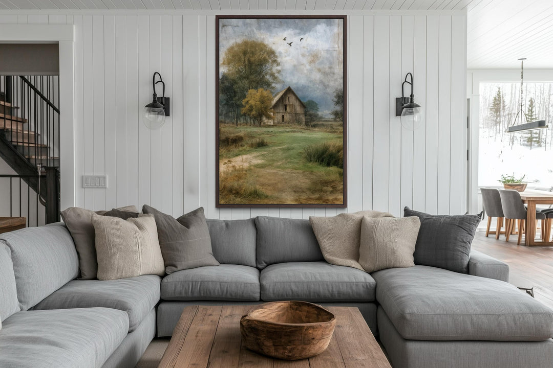 Vertical barn artwork canvas print in a rustic farmhouse living room above a gray sectional sofa.