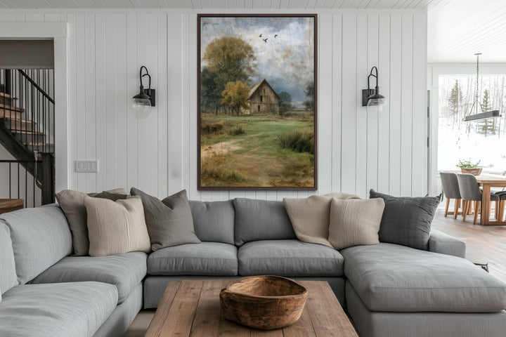Vertical barn artwork canvas print in a rustic farmhouse living room above a gray sectional sofa.