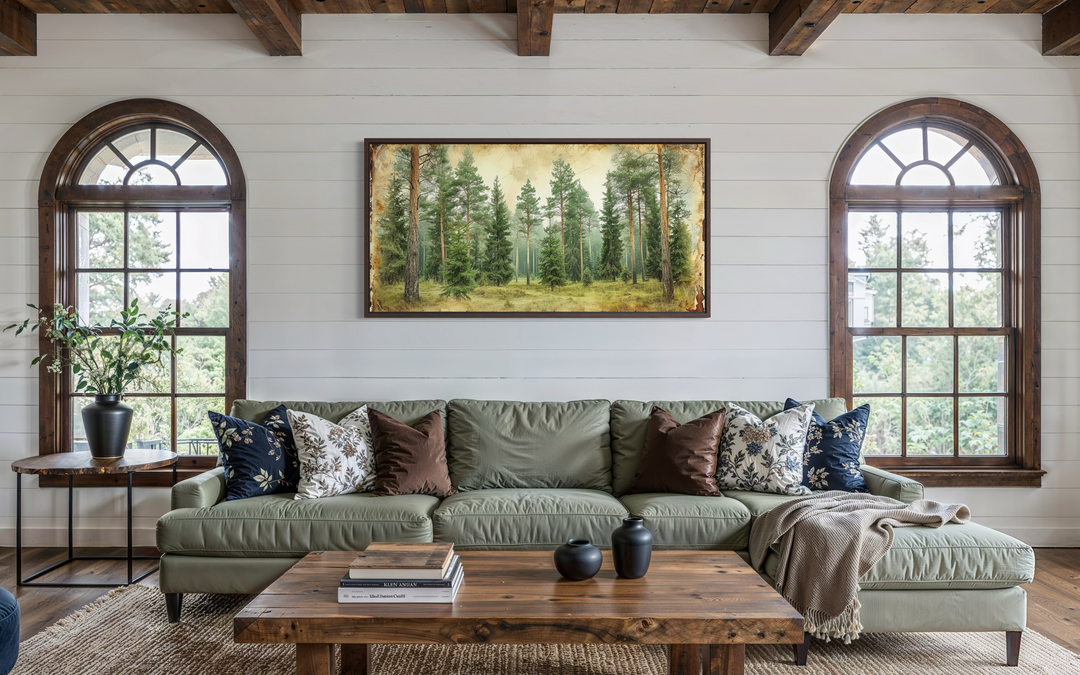 A framed canvas print of a rustic fir tree forest hangs above a green sofa in a farmhouse living room.