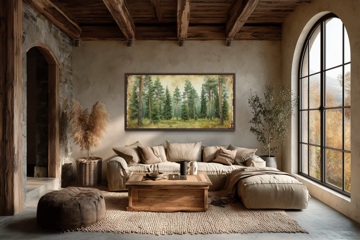 A framed canvas print of a rustic fir tree forest hangs above a sofa in a cozy, earthy living room.