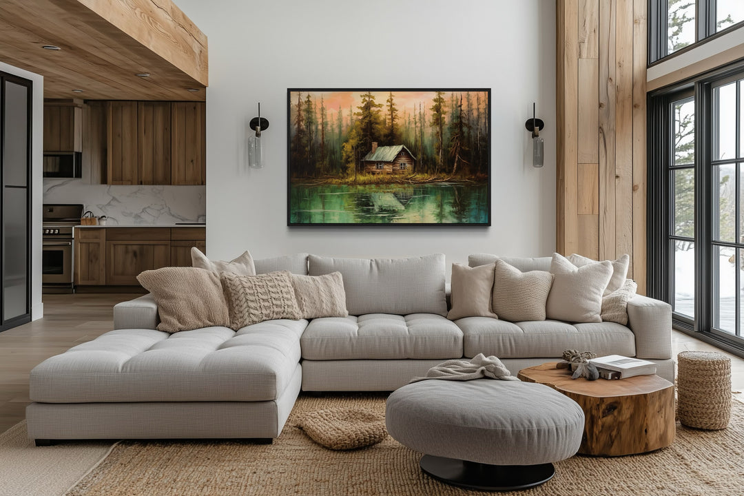Rustic framed canvas wall art of a cabin by a lake, hanging above a modern sectional sofa.