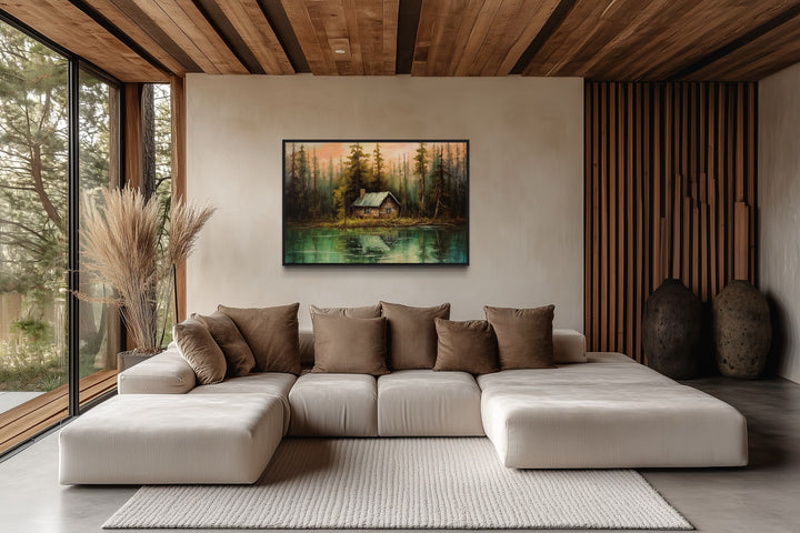 Rustic lake and cabin framed canvas wall art hanging above a modern sectional sofa in a cabin.