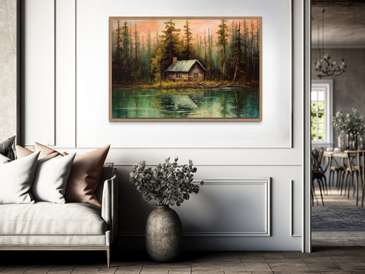 Rustic lake and cabin framed canvas wall art hanging above a sofa in a modern living room.