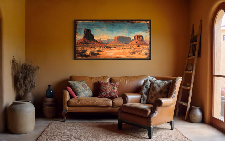 Rustic Monument Valley framed canvas wall art hanging above a leather sofa in a desert-style room.
