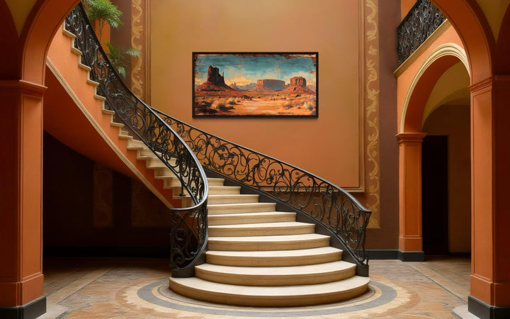 Rustic Monument Valley framed canvas wall art hanging on a wall above a grand spiral staircase.