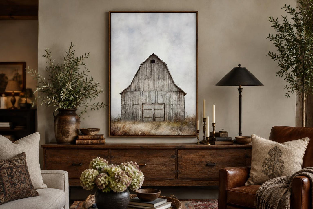 Rustic vertical canvas print of a weathered old barn in a field, framed above a wooden sideboard.
