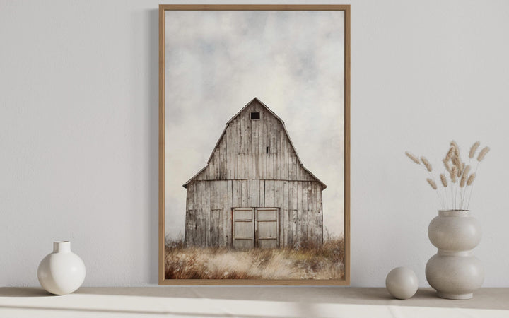 Framed vertical canvas print of a rustic weathered barn in a field with a soft, muted color palette.