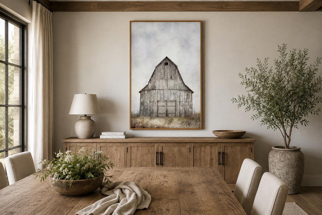 Vertical canvas print of a weathered rustic barn in a field above a wooden sideboard.