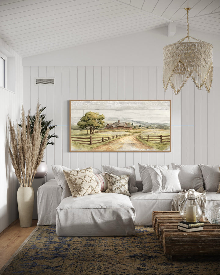 Rustic old barn landscape painting on wood-effect canvas framed above a white sofa in a cozy room.