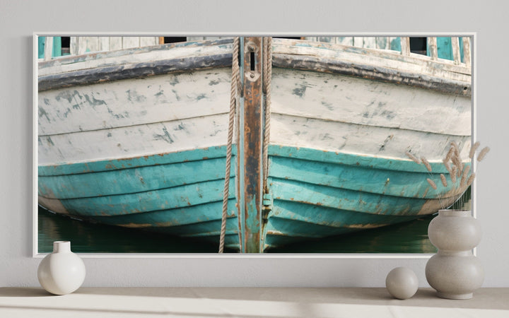Framed canvas wall art of a rustic teal and white boat close-up on a wall with decorative vases.