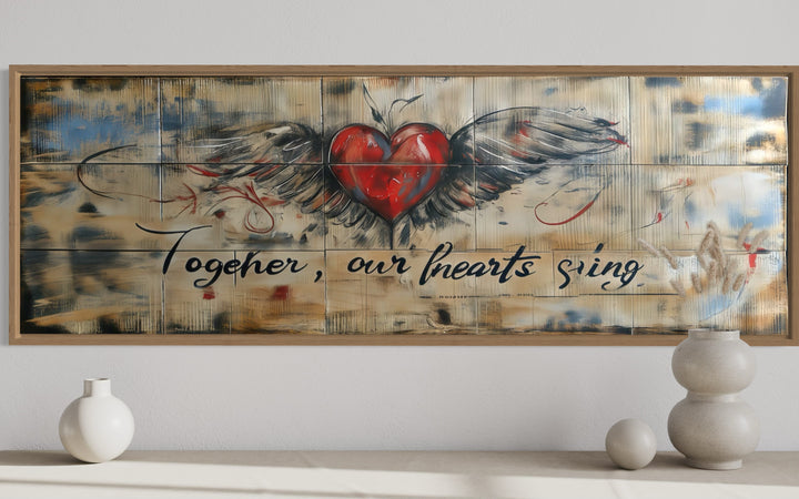 Rustic framed wall art with a winged heart and the text Together Our Hearts Sing over a bed.