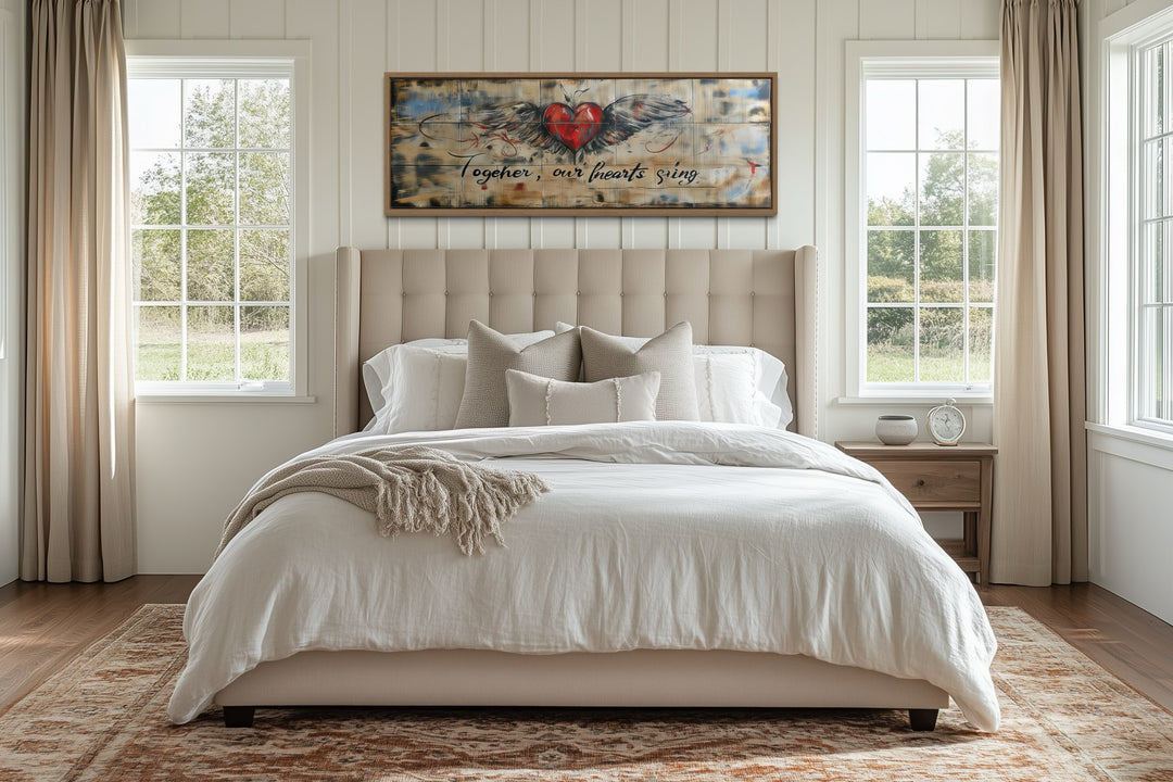 Rustic framed wall art over a bed featuring a winged heart and 'Together our hearts sing' text.