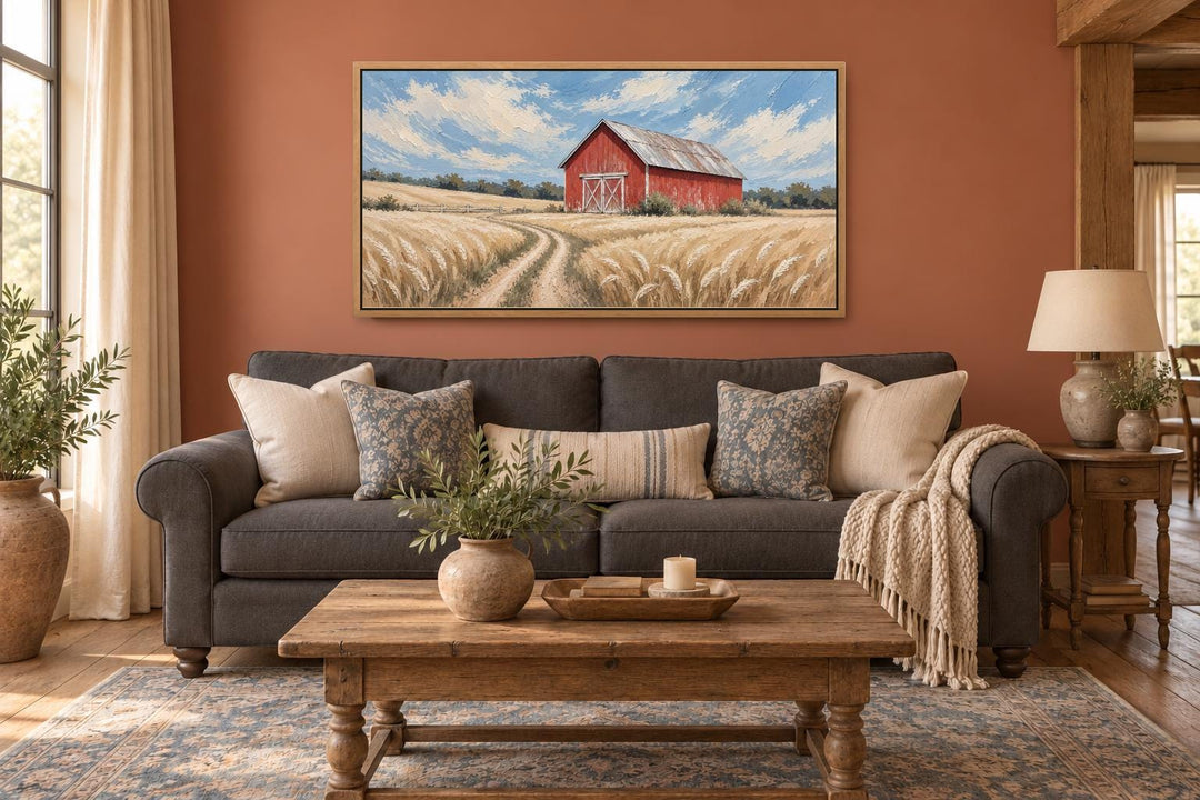 Rustic Red Barn In Wheat Field Landscape Canvas Wall Art above a dark gray sofa in a living room.