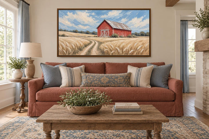 Rustic red barn in a golden wheat field landscape canvas wall art hanging above a sofa.