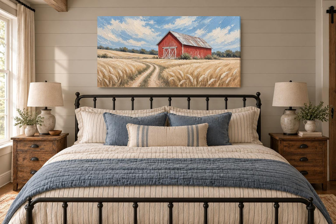 Rustic red barn in a golden wheat field landscape canvas wall art hanging above a bed.