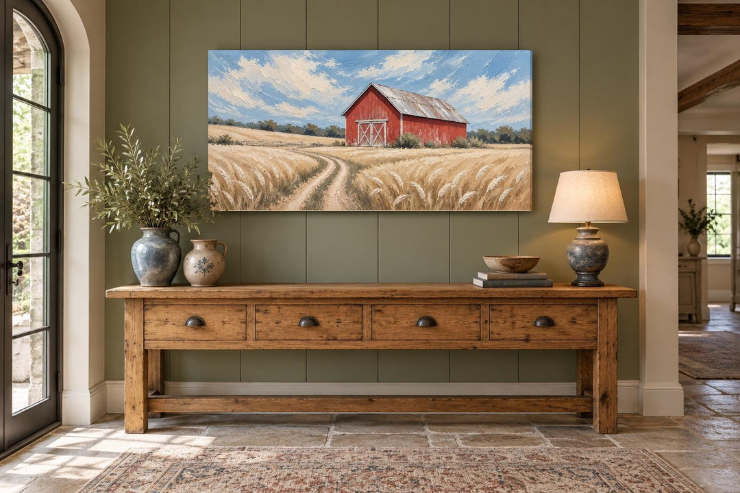 Rustic red barn in a golden wheat field landscape canvas wall art above a wooden console table.