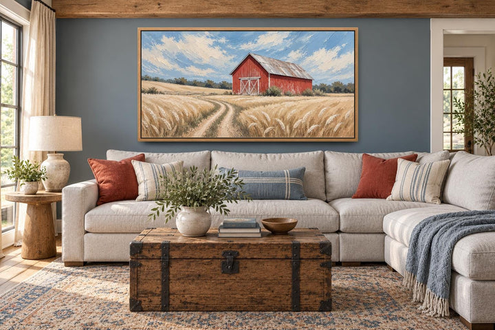 Rustic red barn in a golden wheat field landscape canvas wall art above a neutral sectional sofa.