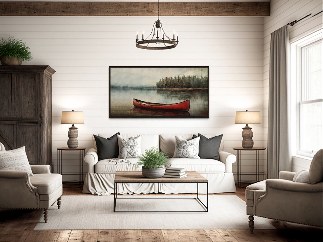 Rustic red canoe on a calm lake framed canvas wall art above a white sofa in a cozy living room.
