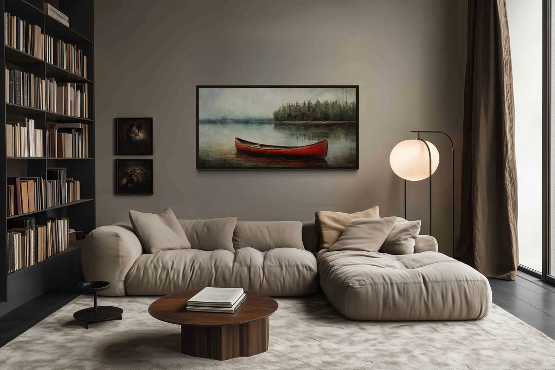 Rustic red canoe in a calm lake framed canvas wall art hanging above a modern beige sofa.