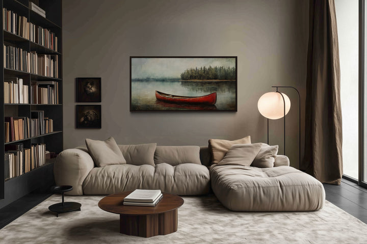 Rustic red canoe in a calm lake framed canvas wall art hanging above a modern beige sofa.