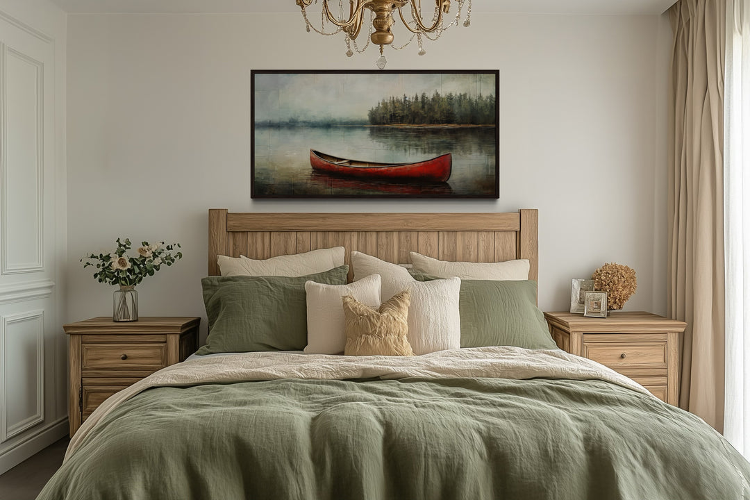Rustic red canoe in the lake framed canvas wall art hanging above a bed in a cozy bedroom.