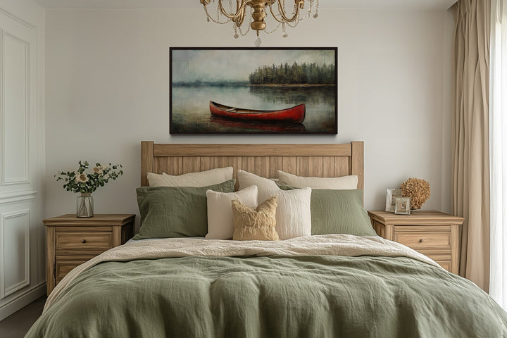 Rustic red canoe in the lake framed canvas wall art hanging above a bed in a cozy bedroom.