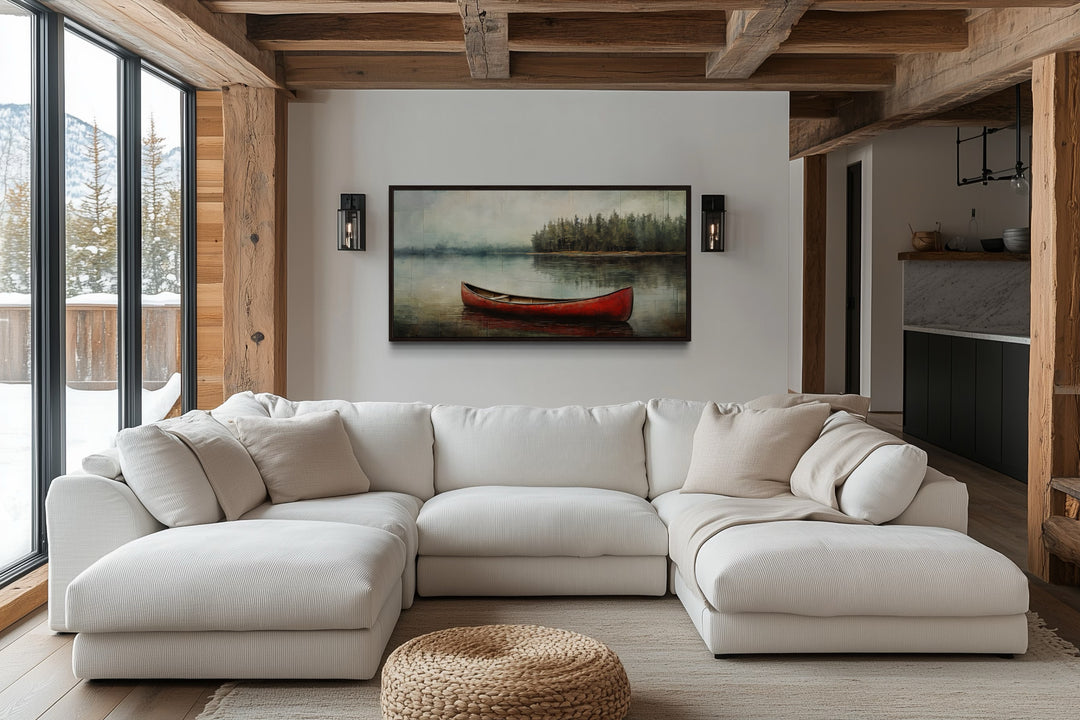 Rustic red canoe in a lake framed canvas wall art hanging above a white sectional sofa.