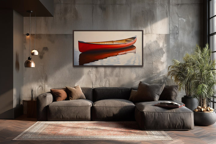 Framed canvas print of a red canoe on calm water hanging above a modern brown sectional sofa.