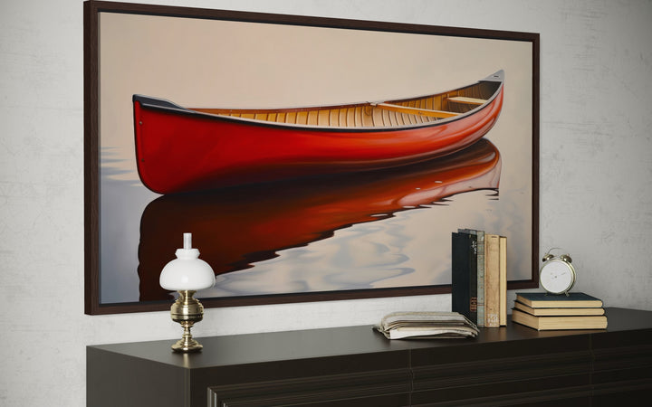 Framed canvas print of a red canoe on calm water, styled above a dark wood dresser.