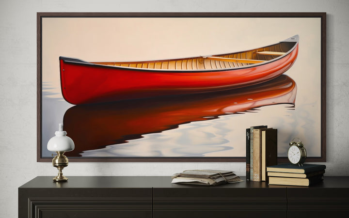 Framed canvas wall art of a red canoe on calm water, displayed above a dark wood dresser.