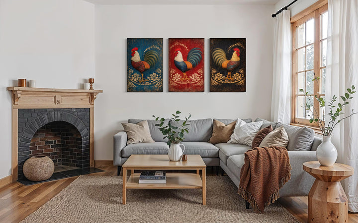 Three-panel rustic rooster canvas wall art set displayed above a grey sectional in a farmhouse room.