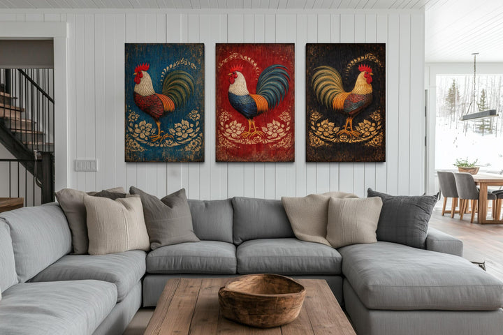 Three-panel rustic rooster canvas art set displayed on a white wall above a gray sectional sofa.