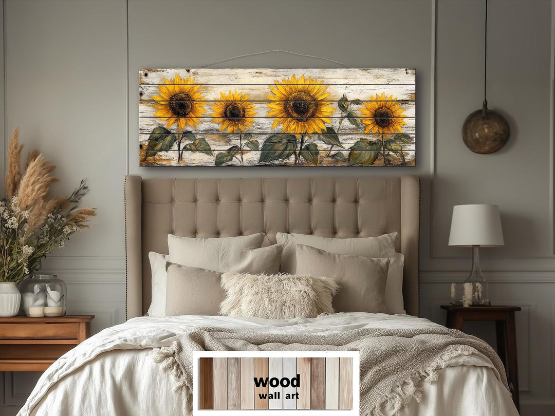 Rustic sunflower wall art on a long whitewashed wood panel hanging above a neutral-toned bed.