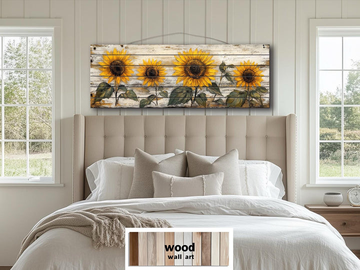 Rustic sunflower wall art on a long whitewashed wood panel hanging above a bed in a farmhouse room.