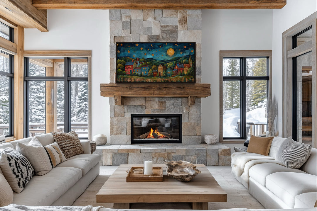 Rustic village wall art with stars and moon displayed above a stone fireplace in a cozy living room.