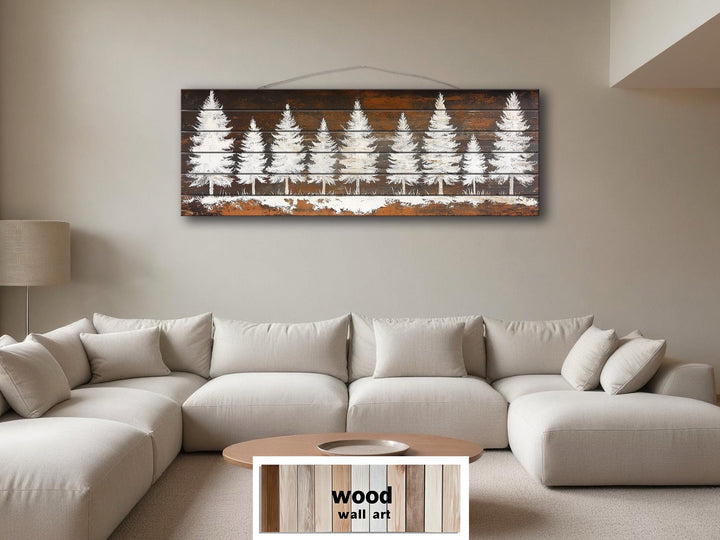 Rustic white pine tree silhouettes on a long, narrow distressed wood wall art piece above a sofa.