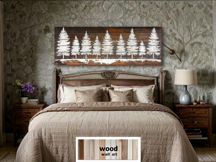 Rustic white pine tree silhouettes on a long, narrow distressed wood wall art piece above a bed.