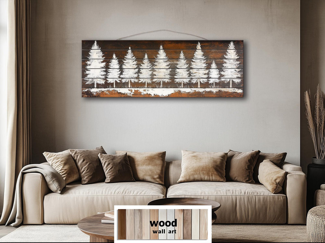Rustic white pine tree silhouettes on a long, narrow distressed wood wall art piece above a sofa.