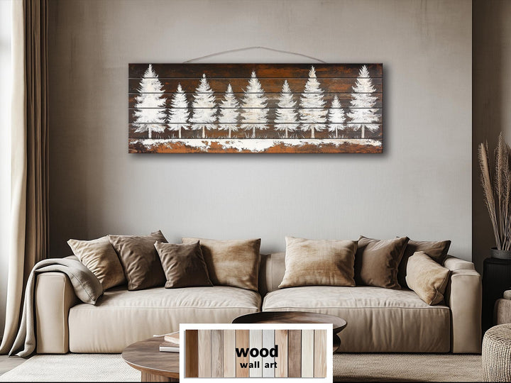 Rustic white pine tree silhouettes on a long, narrow distressed wood wall art piece above a sofa.