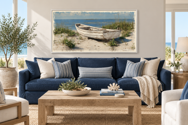 Old white boat on the beach coastal framed canvas wall art hanging above a blue sofa.